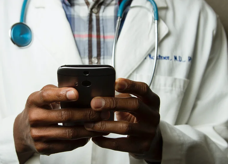 A physician checks an app on his smartphone. 
