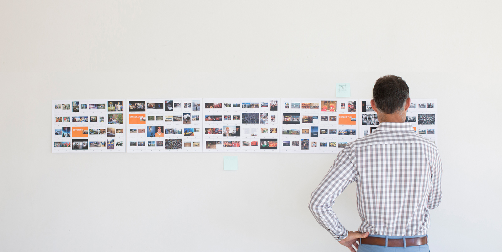 Man standing in front of a white wall with small photos displayed