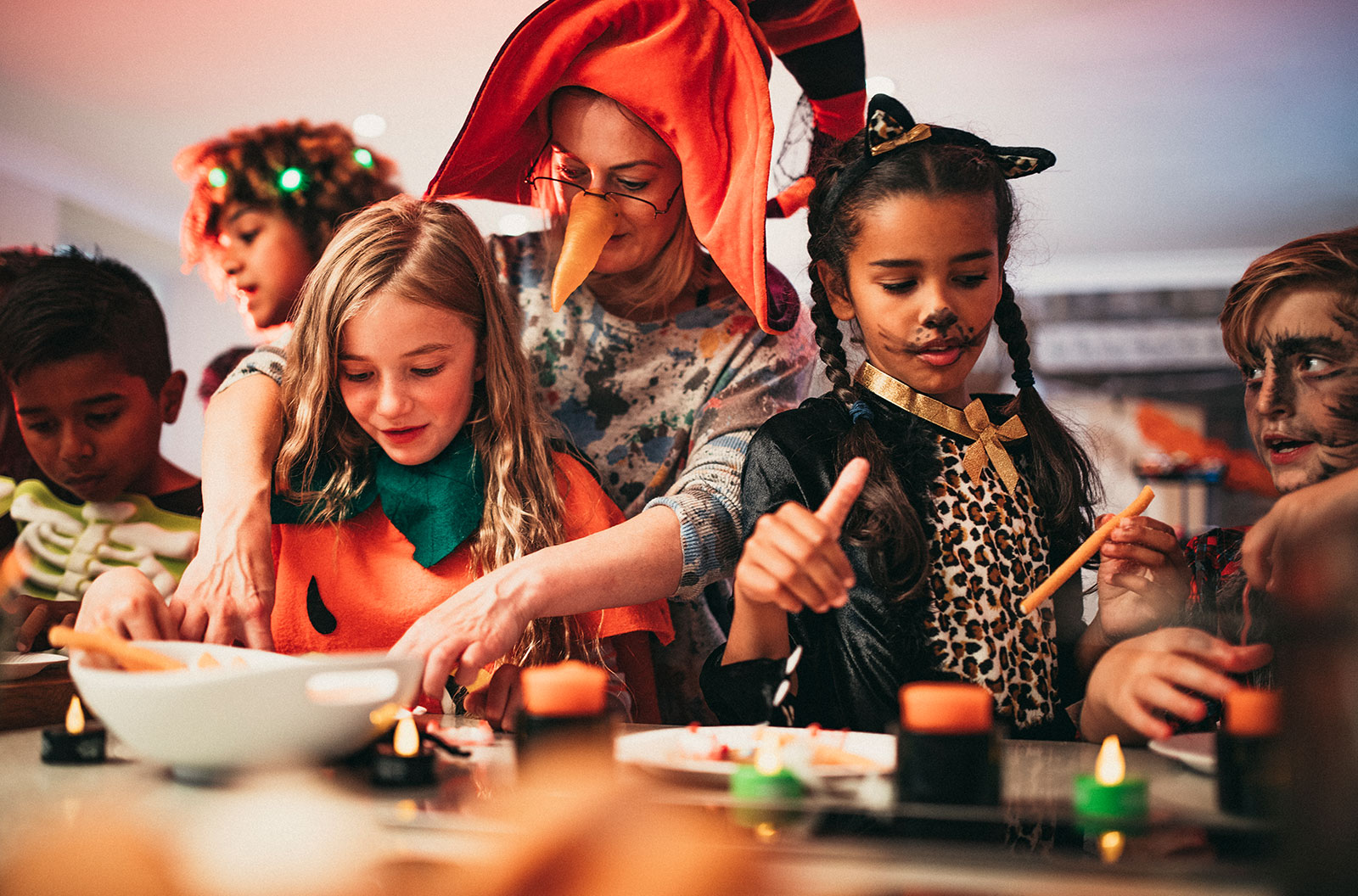 Costumed children sitting in a line deciding which foods to eat while at a Halloween party