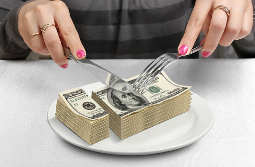 Hands cut money on plate, reduce funds concept