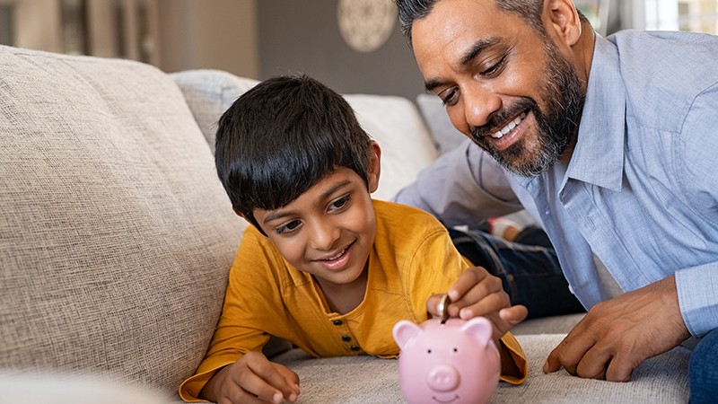 parent-young-child-saving-into-piggy-bank