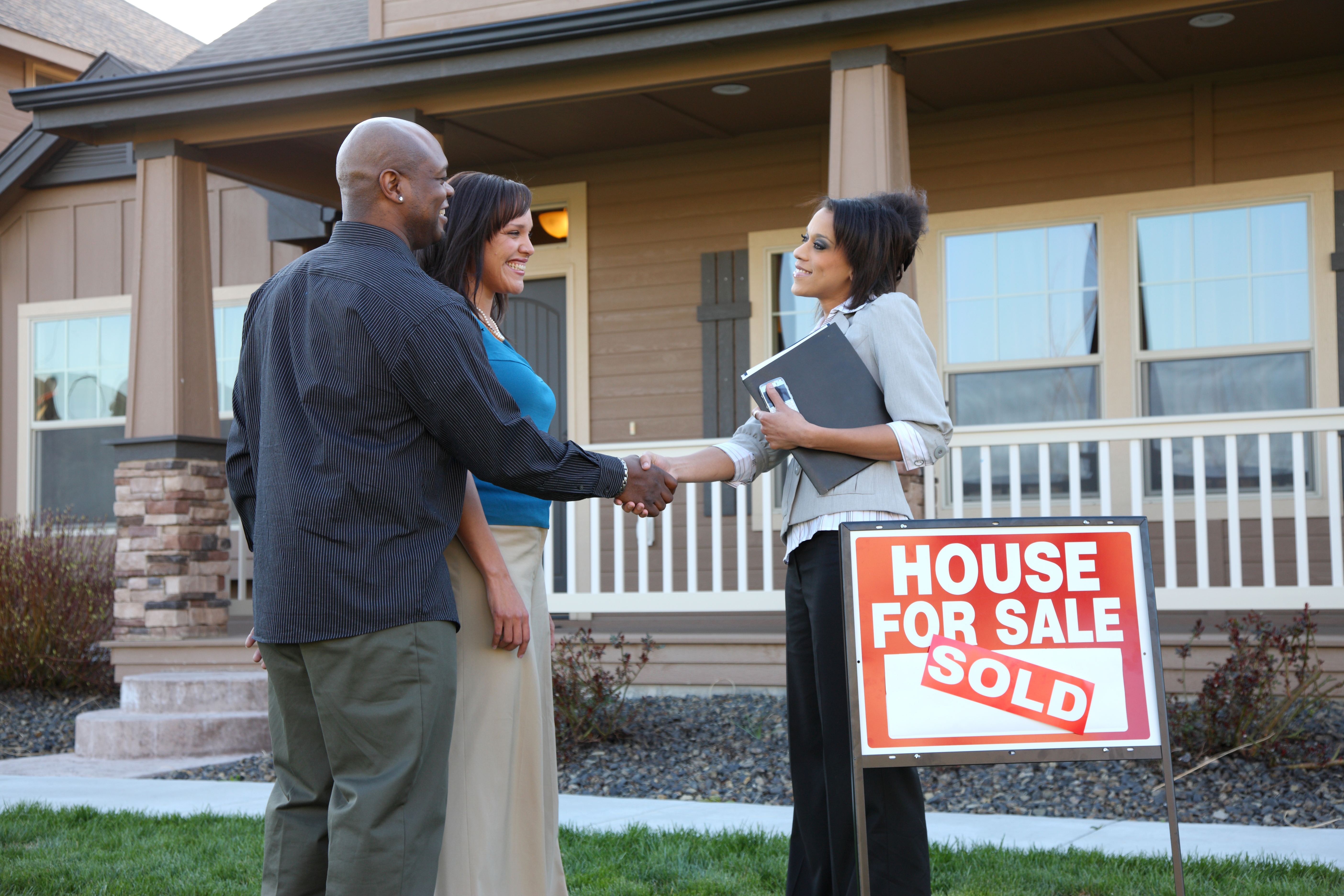 Couple shakes hands with realtor outside new house