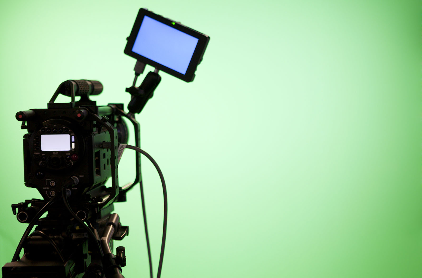 A professional camera in front of a green screen set up. 
