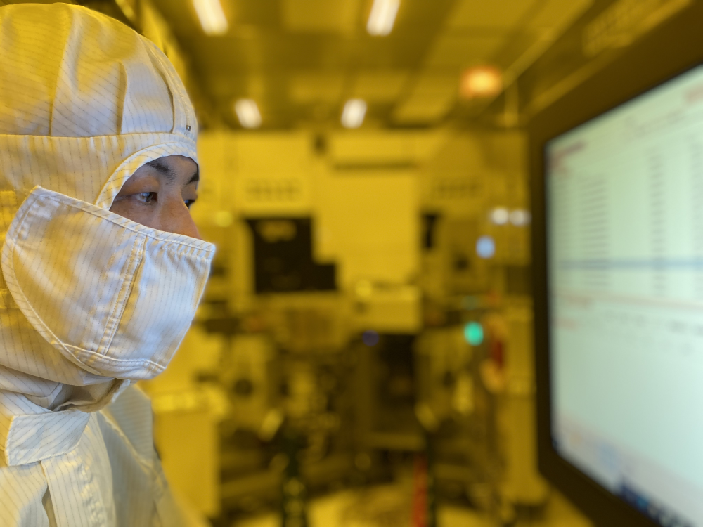 クリーンルームにて、半導体製造装置における処理条件を調整する谷口氏