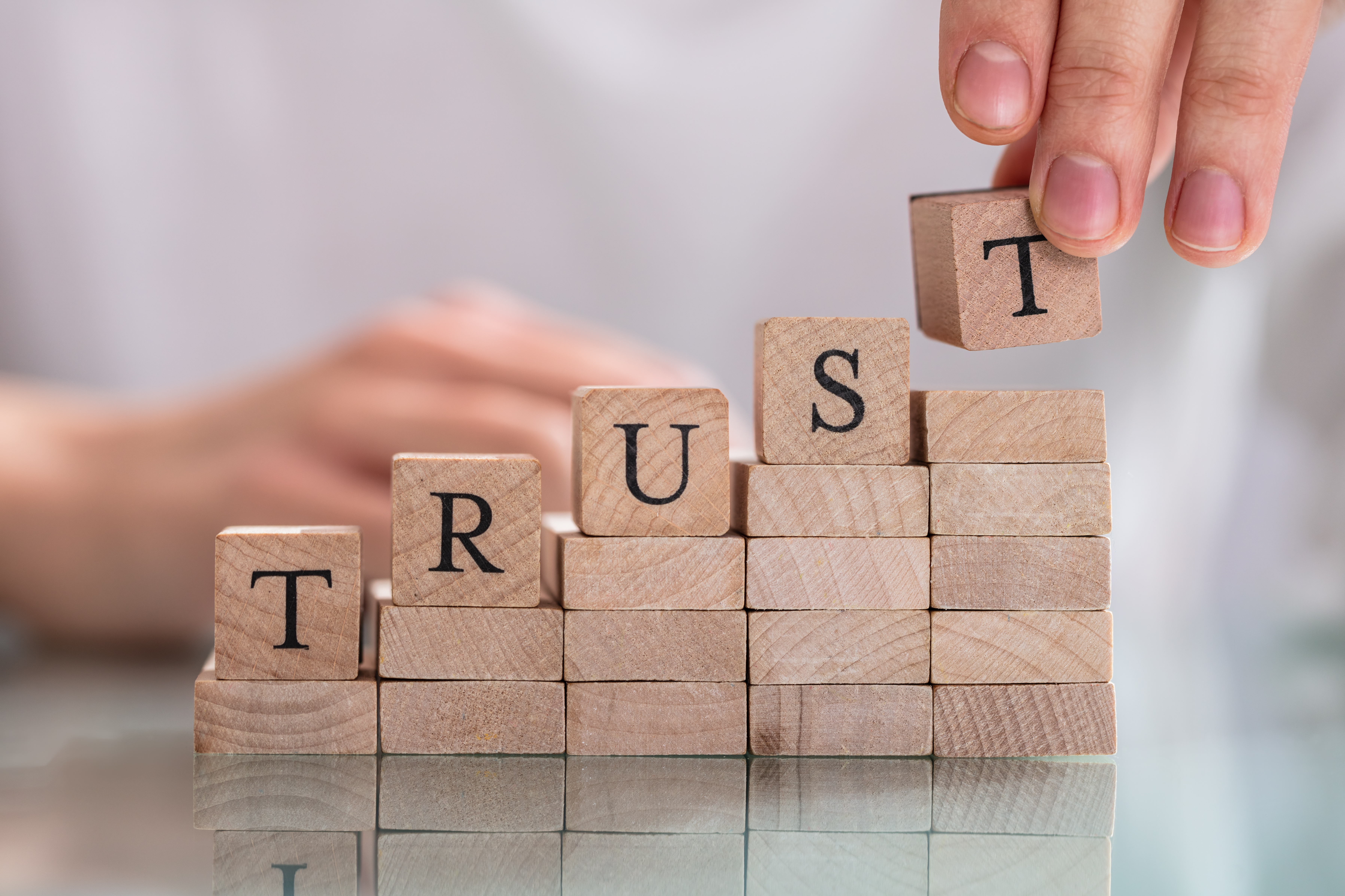 Woman's Hand Placing Last Alphabet Of Word Trust