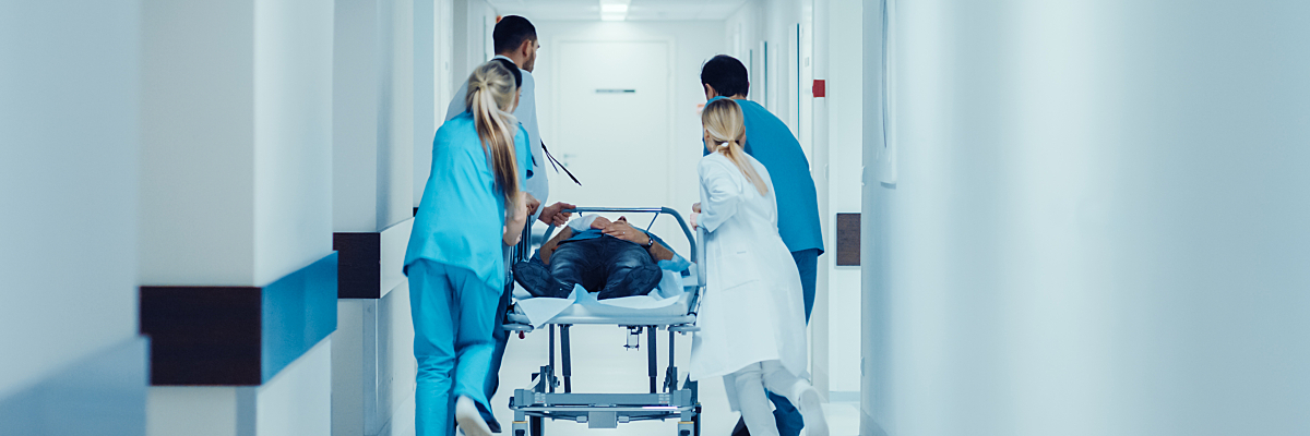 Emergency providers roll a patient on a gurney through the ED. 