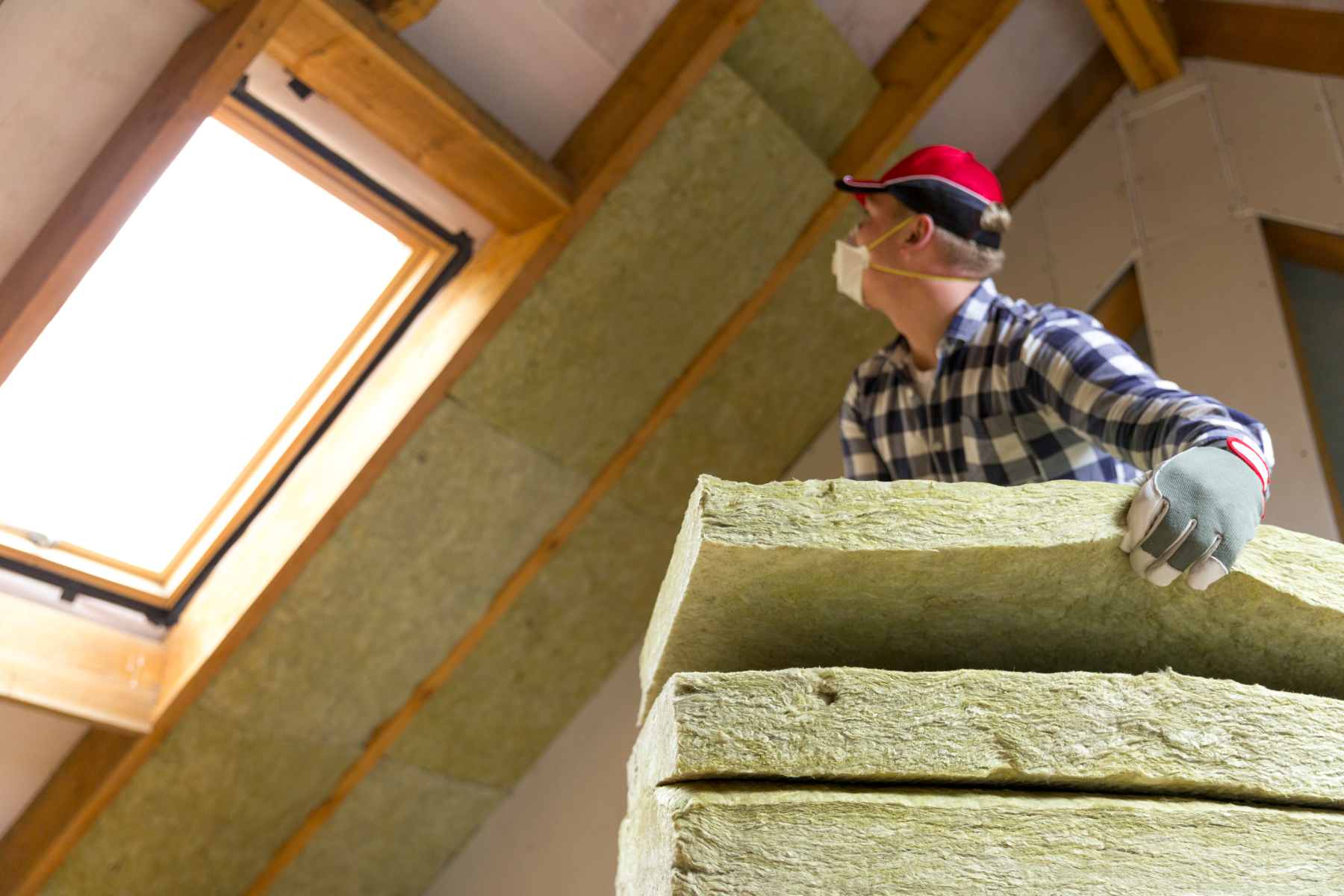 Man installing thermal roof insulation layer - using mineral wool panels. Attic renovation and insulation concept