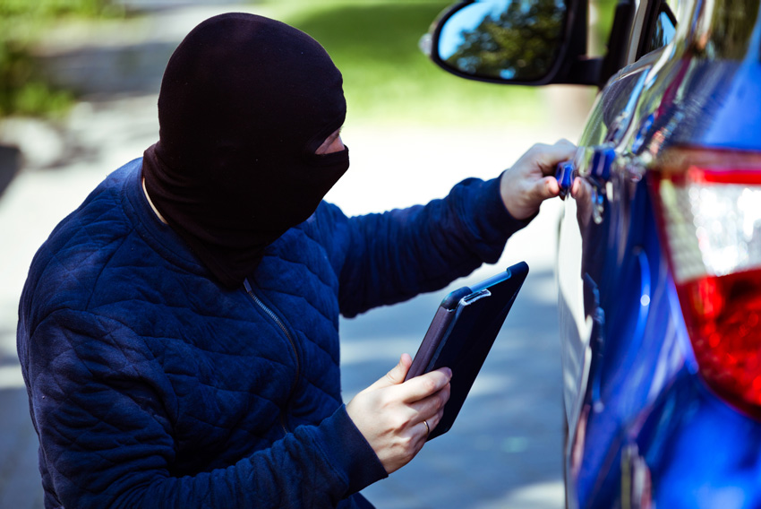 Lopov poskuša vdreti v parkiran avto - Simbolna slika o zavarovanju avta pred krajo