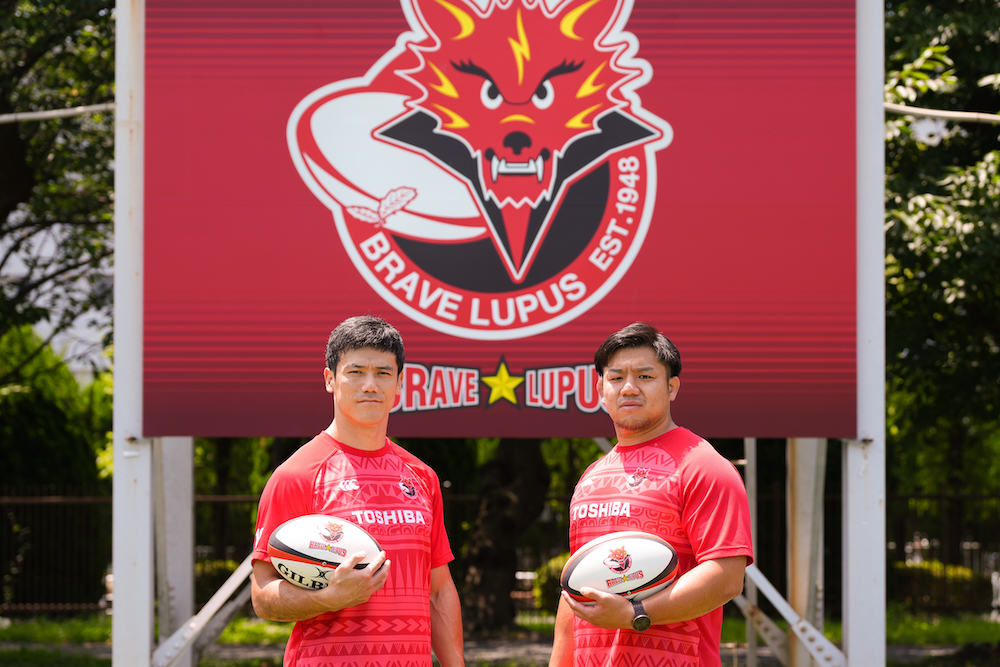 Toyoshima and Hashimoto in front of the Brave Lupus support flag