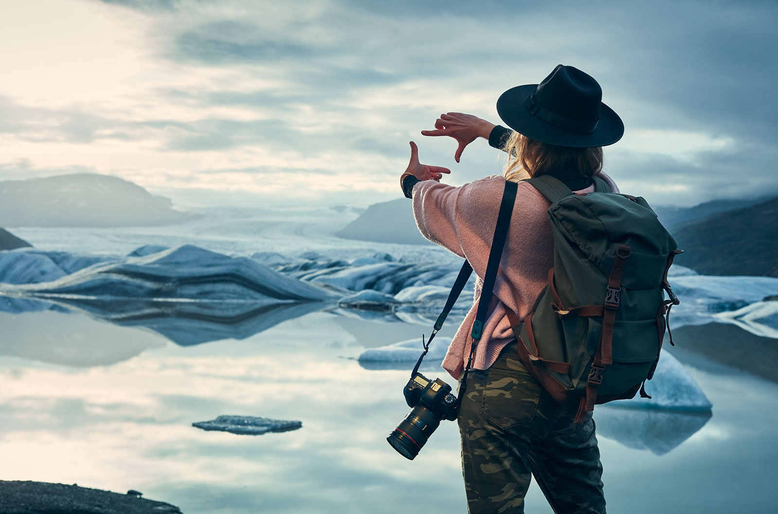 Young woman at glacier lagoon framing her shot to take photographs