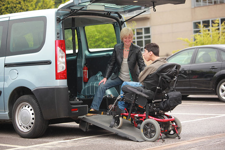 Man in wheelchair boarding Wheelchair Accessible Vehicle (WAV) using a ramp