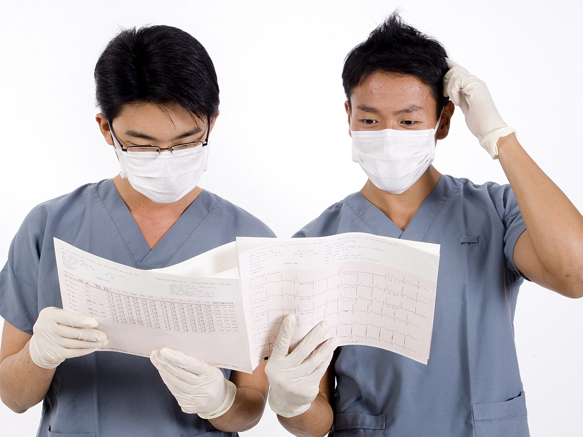 Two doctors struggle to read an ecg printout highlighting the challenges in decision making. 