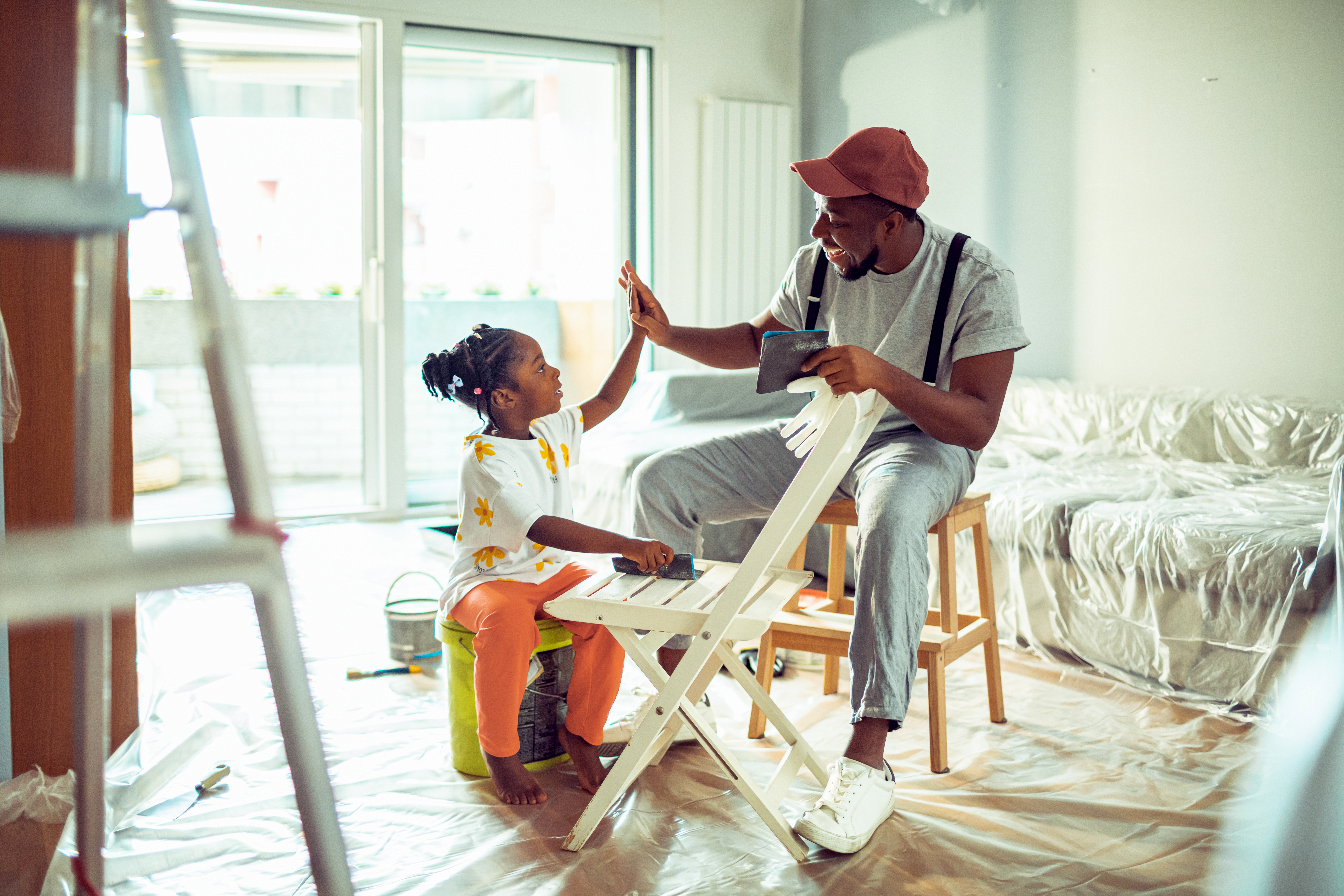 Father painting a chair with his daughter