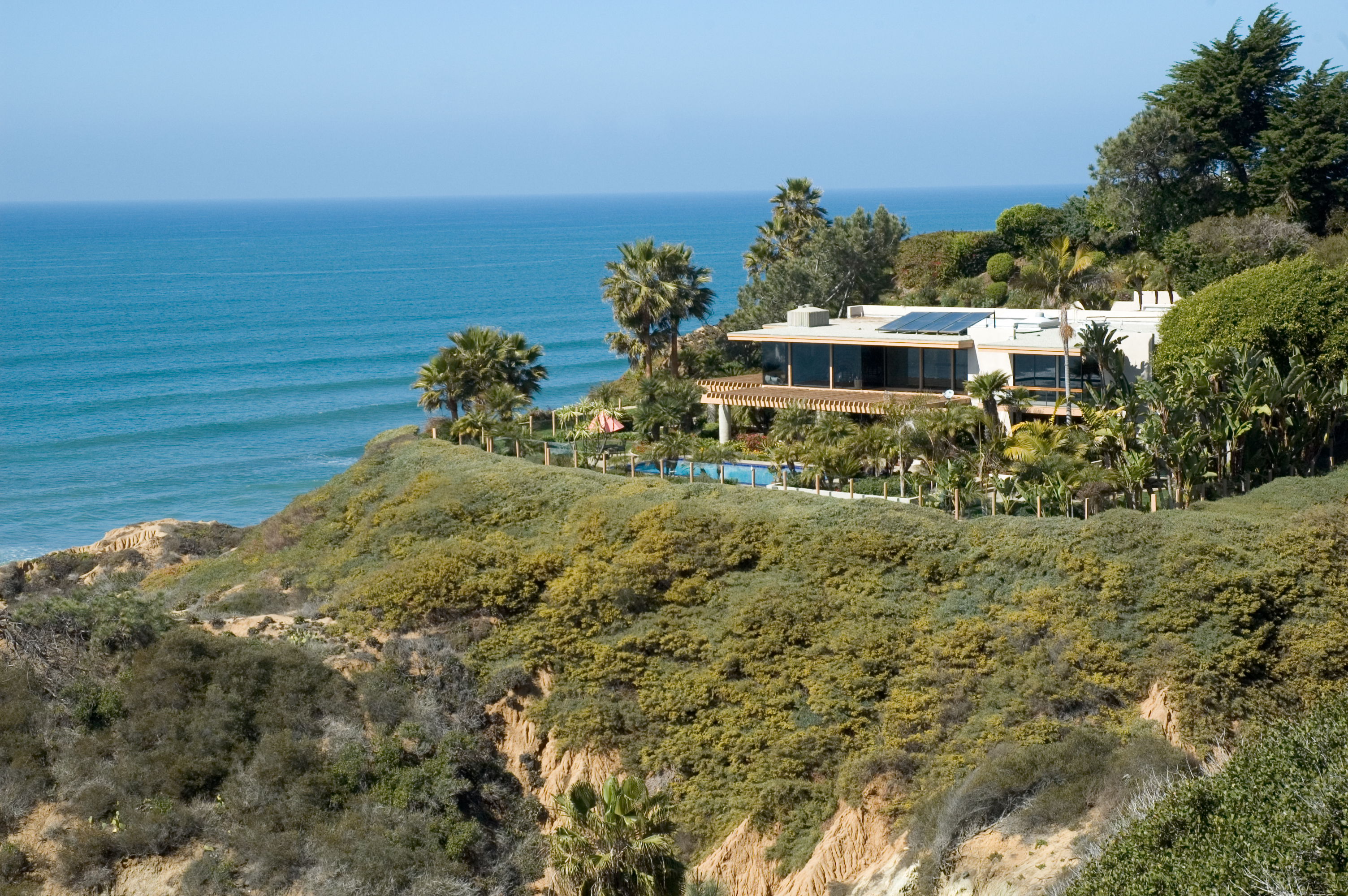 Beach house on top of cliff with sea in background