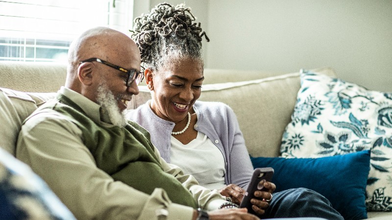Senior couple looking at smartphone in living room of suburban home