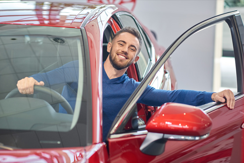 Mlad moški v rdečem avtu - Simbolna slika za kako izbrati pravi avto