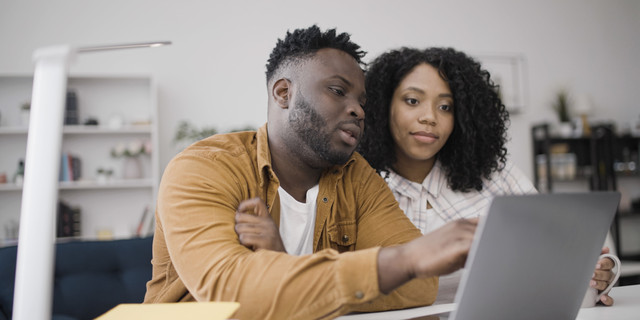 Young black couple discusses options as they choose a school for their child online
