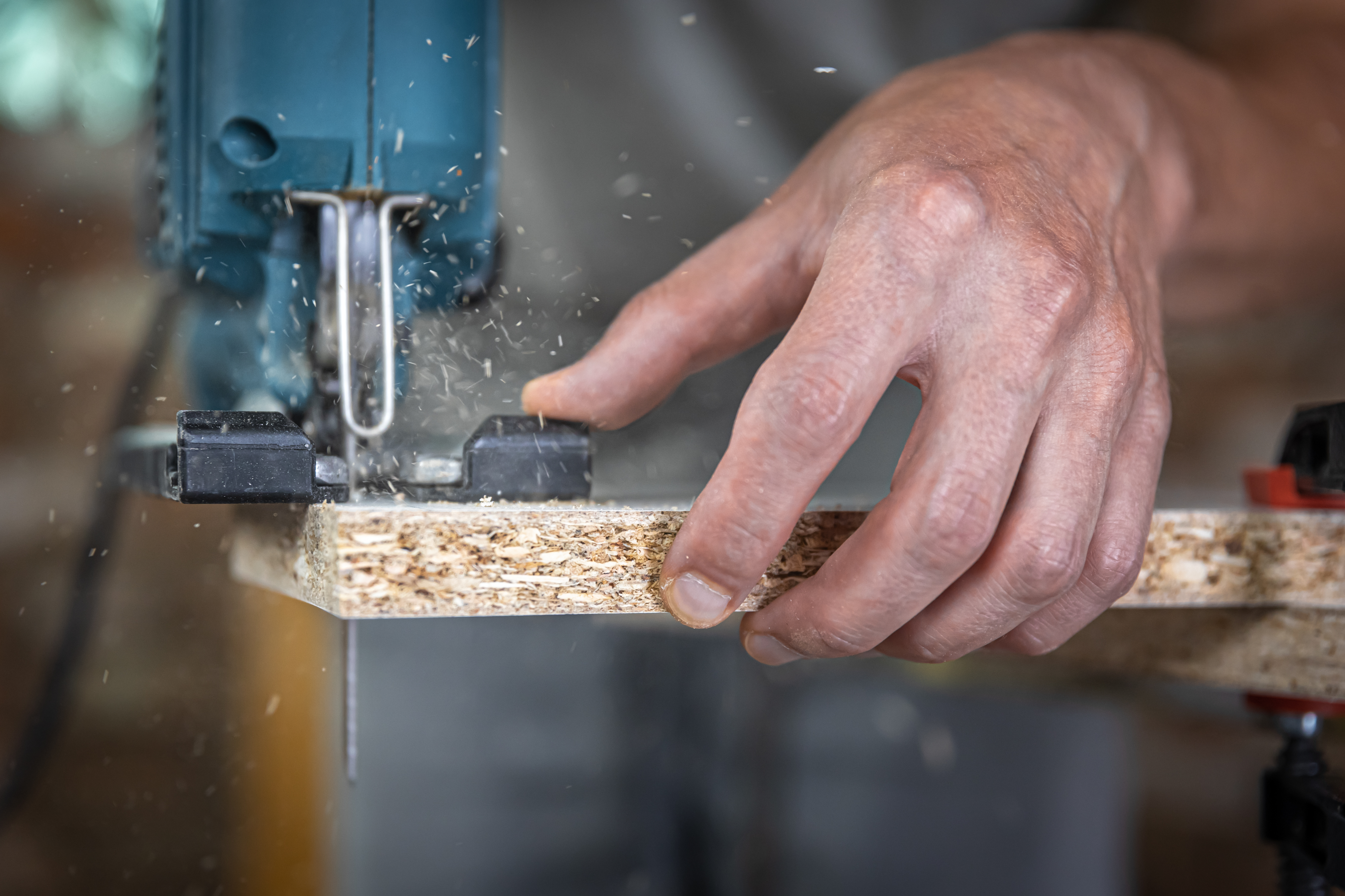 close-up-carpenter-s-hands-process-cutting-wood-with-jigsaw.jpg
