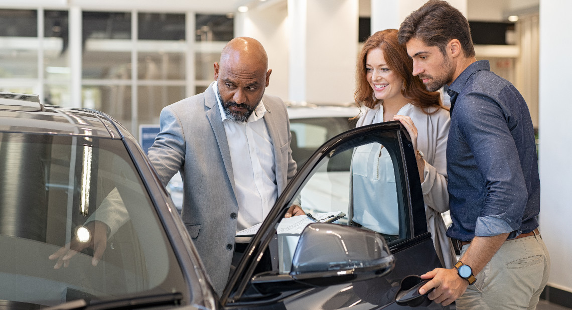 Salesman showing car features to couple