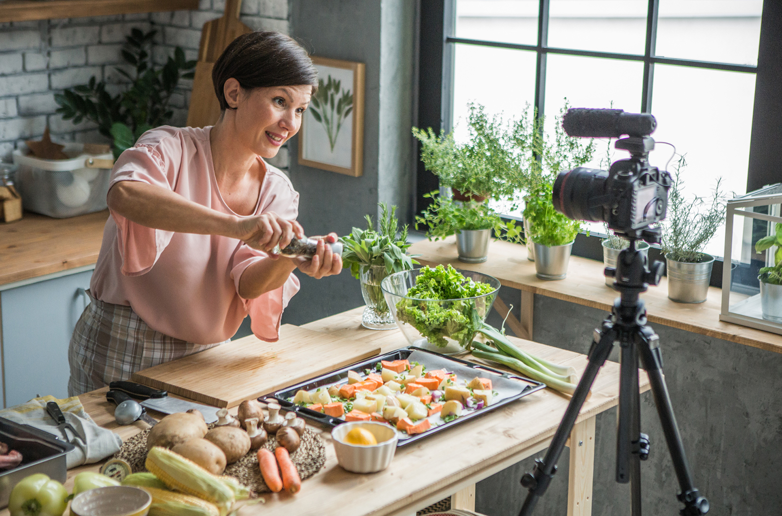 Woman in a kitchen cooking in front of a camera set up. 