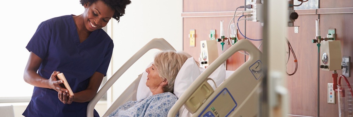 Nurse reviews data with patient in hospital room. 