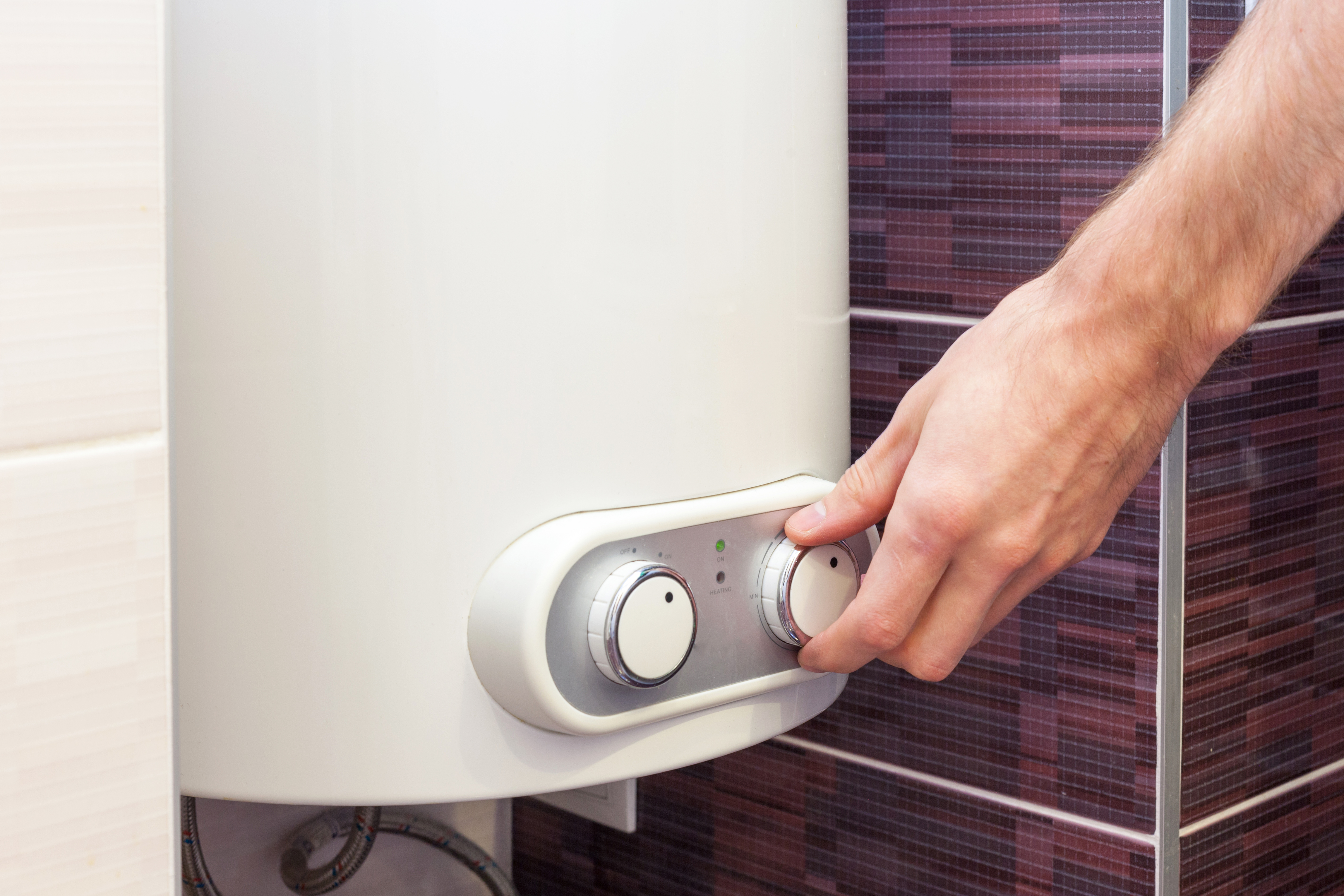 Man hands setting the temperature of water in Electric Boiler