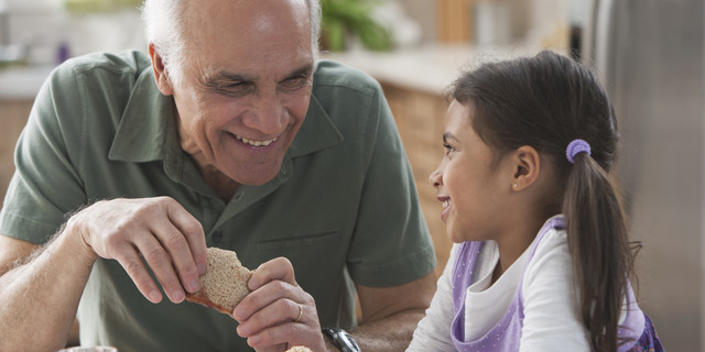 Grandfather and granddaughter eating sandwiches