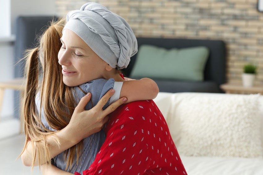 Ženska s turbanom, ki se zdravi zaradi raka, objema mladoletno hčerko - simbolna fotografija za čnake o najbolj pogostih vrstah raka pri ženskah