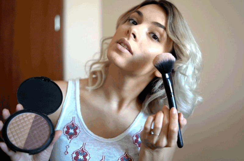  Young woman applying makeup on her face